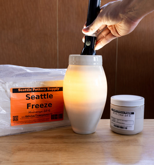 Showing Seattle Freeze Mid-Range Translucent Porcelain lit up by a flashlight, with the bagged clay and clear glaze used next to the vessel